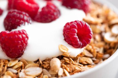 Tahta bir masada tahıllı kahvaltı, yoğurt ve taze ahududu. Sağlıklı atıştırmalıklar. Makro fotoğraf.