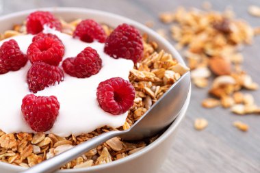 Tahta bir masada tahıllı kahvaltı, yoğurt ve taze ahududu. Sağlıklı atıştırmalıklar. Makro fotoğraf.