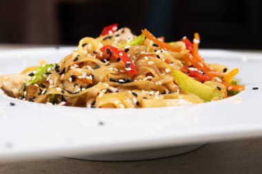 Beyaz tabakta biber, tavuk ve havuçlu Tayland yemeği. Asya restoranı yemekleri.