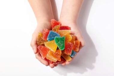 Beyaz arka planda izole edilmiş bir çocuk elinde renkli tatlı jöle şekeri. Üst görünüm.