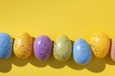 Sarı arka planda Paskalya renkli yumurtalar. en üstteki görünüm.