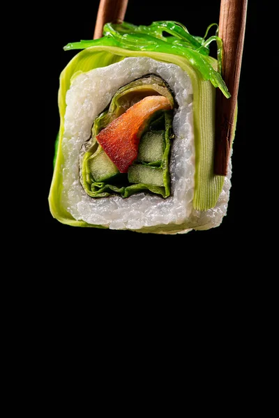 素食概念 一个寿司卷与纸 黄瓜和卷心菜 鳄梨与筷子在黑色背景 宏观照片 — 图库照片