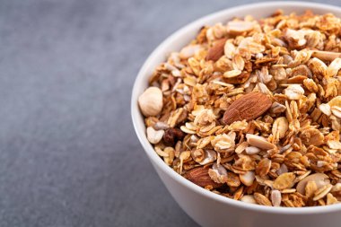 Beyaz kasede badem bulunan taze granola. Taş grisi arka plan. Kahvaltı yemeği. Makro fotoğraf.