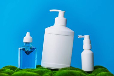 Jel dezenfektanı. Şampuan kutusu. Gırtlak spreyi. Alerjiye karşı hijyen. Mavi arka planda yeşil çimen.