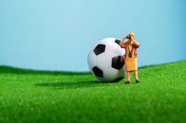 Bahçesinde futbol topu ve turist fotoğrafçısı olan yaratıcı bir fotoğraf. Macro vuruldu. Spor geçmişi. Minyatür insanlar.