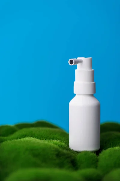 Lekarski Spray Gardła Białej Plastikowej Butelce Zielonej Trawie Niebieskie Tło — Zdjęcie stockowe