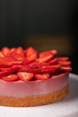 Sweet cheesecake with strawberries fruit on a stone table. Summer dessert food concept.