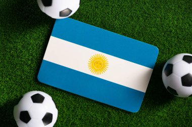 Flag of Argentina. Football balls on a green lawn. World Cup 2022. Top view.