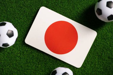 Flag of Japan. Football balls on a green lawn. World Cup 2022. Top view.
