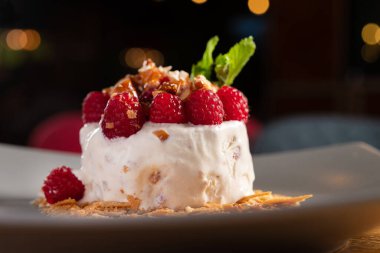 Delicious dessert of ice cream, fresh raspberries and nuts on the table in the restaurant.