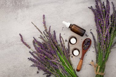 Production of perfumes from lavender. Cosmetologist's office. Oil and flowers on a stone table background.