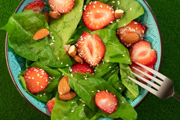 Diet food dish. Strawberry salad with spinach and almonds. healthy and vegan food background. Top view.