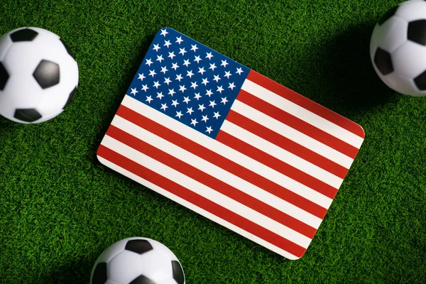 Flag of USA. Football balls on a green lawn. World Cup 2022. Top view.