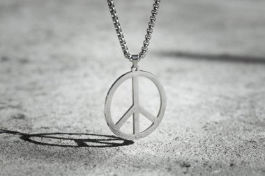 Asfaltın arka planında metal barış sembolü kolyesi var. Ukrayna 'daki savaşı durdurun.