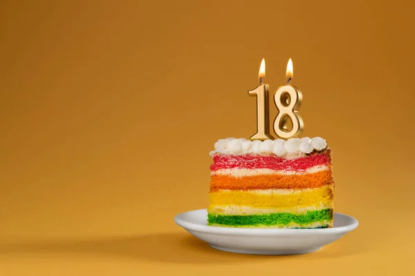 Rainbow cake dessert with 18 number candles birthday concept. Reaching age of majority background.