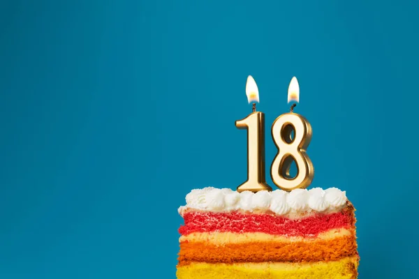 Rainbow cake dessert with 18 number candles birthday concept. Reaching age of majority background.