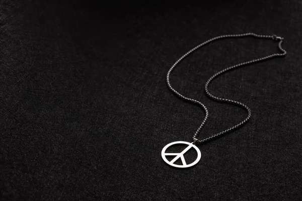 Necklace with a mark of peace on a black old background. Stop war in Ukraine. Anti war concept.
