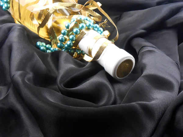 Bouteille de vin de champagne avec diamants bleus sur fond matériel noir — Photo