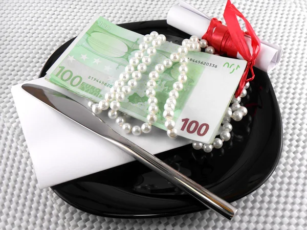 Money on plate, knife, diamonds and gift bow on white paper — Stock Photo, Image