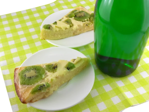 Kiwi tasty cake close up at plate and champagne bottle — Stock Photo, Image