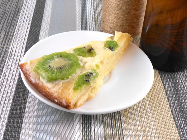 Kiwi tasty cake close up at plate with vintage wine bottle — Stock Photo, Image