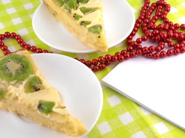 Kiwi gâteau savoureux près de la plaque et des diamants rouges — Photo