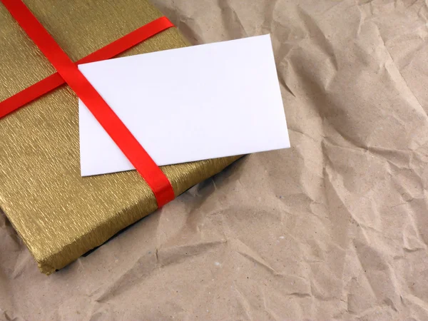 Caja de regalo de oro con lazo rojo en papel viejo vintage —  Fotos de Stock