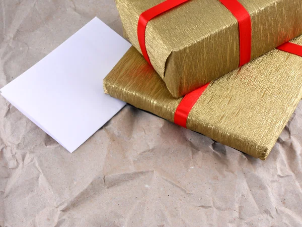 Золотая подарочная коробка с красным бантом на винтажной гранж-бумаге — стоковое фото