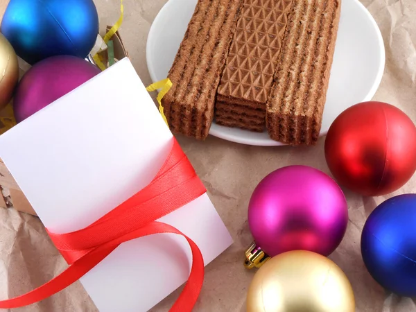 Süße Waffeln mit Weihnachtskugeln und weißer Einladungskarte — Stockfoto