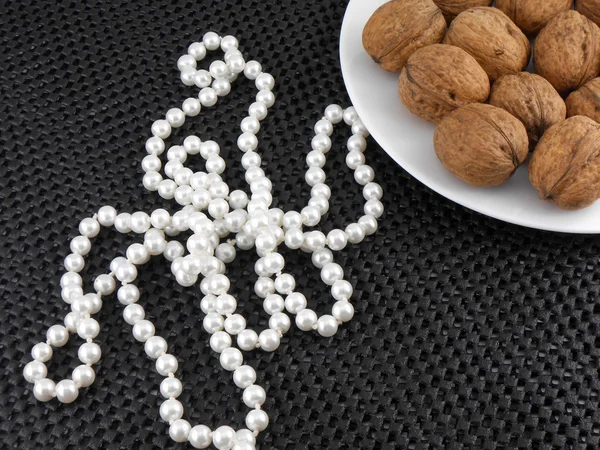 Walnuts on a white plate with white pearls — Stock Photo, Image