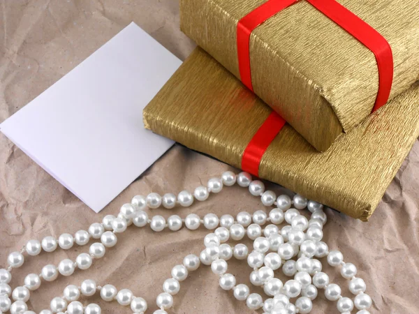 Goldene Geschenkbox mit roter Schleife mit Perlen auf altem Papier — Stockfoto