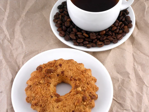 Kaffee und Bohnen auf weißem Teller mit süßem Kuchen — Stockfoto
