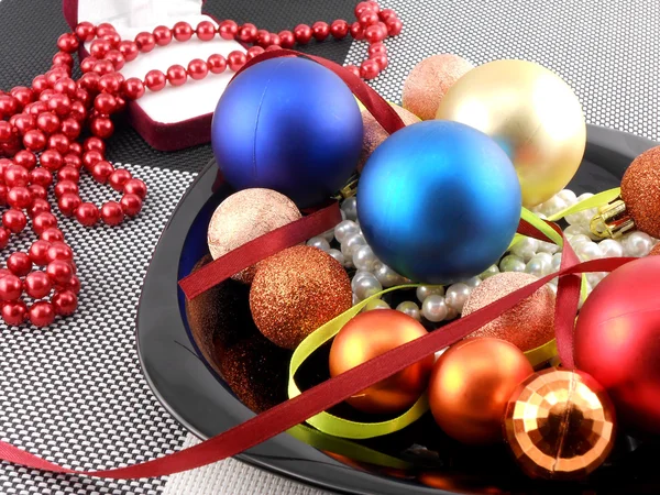 Bola de Navidad decorativa y perlas en un plato, vacaciones de año nuevo — Foto de Stock