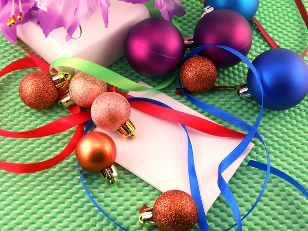 Een witte cadeau met een groene lint en Nieuwjaar ballen — Stockfoto