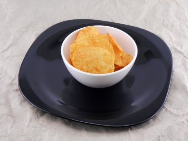 Lezzetli patates cipsleri beyaz tabakta eski kağıt üzerinde