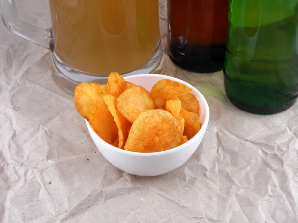 Bierflasche und Kartoffelchips auf weißem Teller — Stockfoto