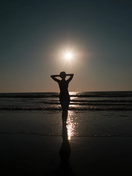 Uma menina e um pôr do sol no mar — Fotografia de Stock