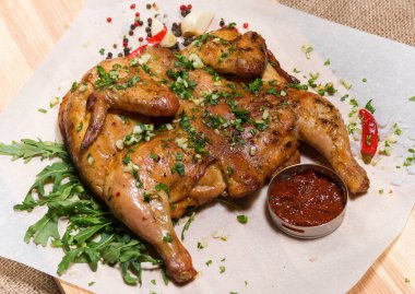 Ahşap bir tahtanın üstünde ızgara tavuk ve sos..