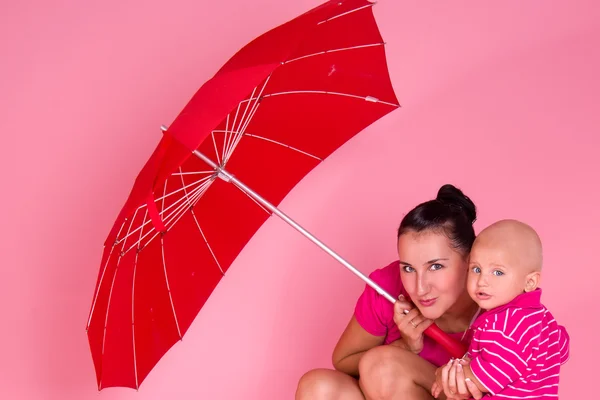 Mãe e filho sob um guarda-chuva vermelho — Fotografia de Stock