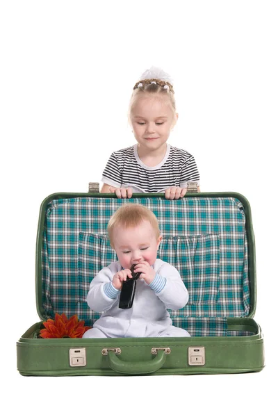 Sister and brother, sitting in an old green suitcase — Stock Photo, Image