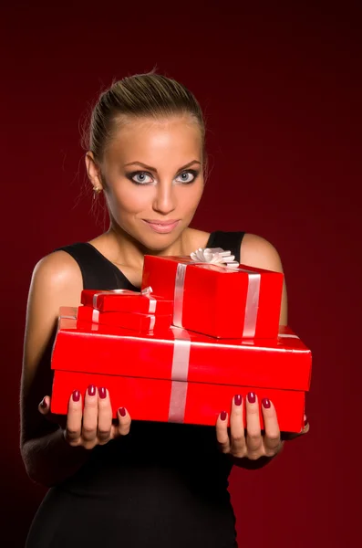 Chica en un vestido negro con regalos en las manos — Foto de Stock