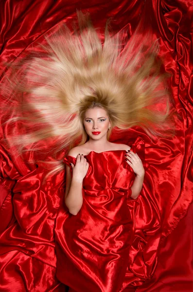 Blonde with long hair on red fabric — Stock Photo, Image