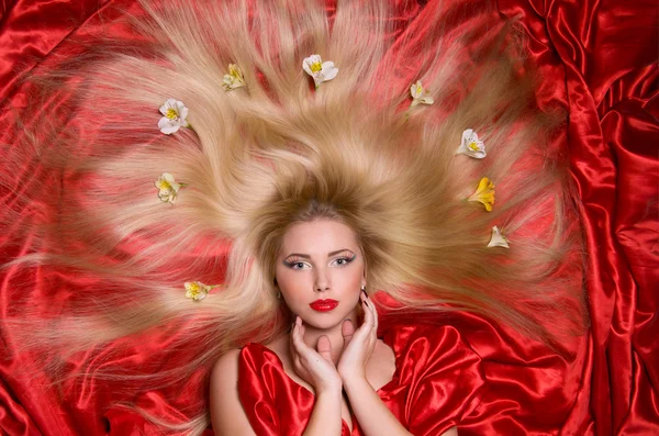 Blonde with long hair on red fabric — Stock Photo, Image