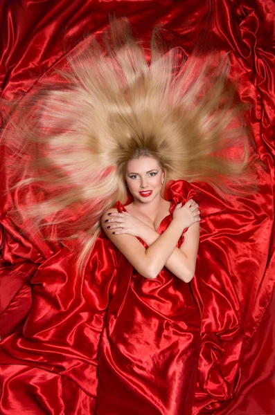 Blondine mit langen Haaren auf rotem Stoff — Stockfoto
