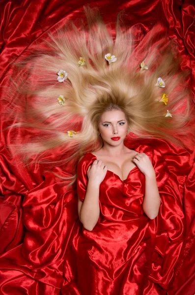 Blonde with long hair on red fabric — Stock Photo, Image