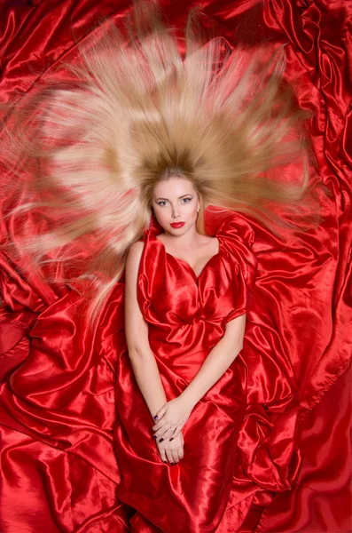 Blonde with long hair on red fabric — Stock Photo, Image