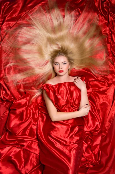 Блондинка с длинными волосами на красной ткани — стоковое фото