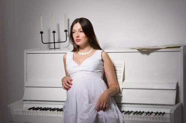 Terhes nő közelében fehér zongora — Stock Fotó