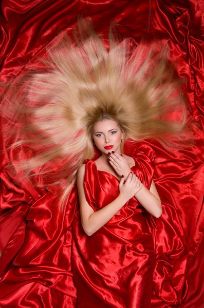 Blonde with long hair on red fabric — Stock Photo, Image