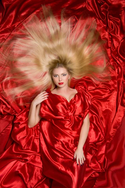 Blonde with long hair on red fabric — Stock Photo, Image